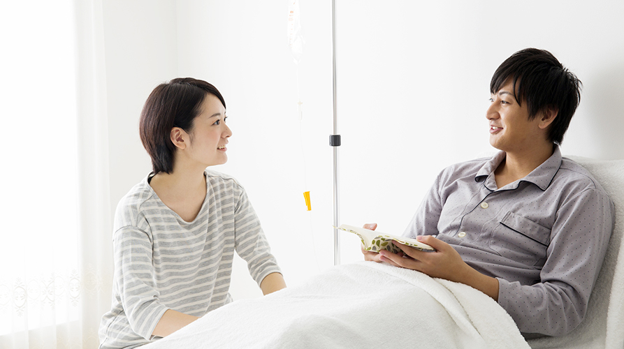入院している夫と話す妻のイメージ画像