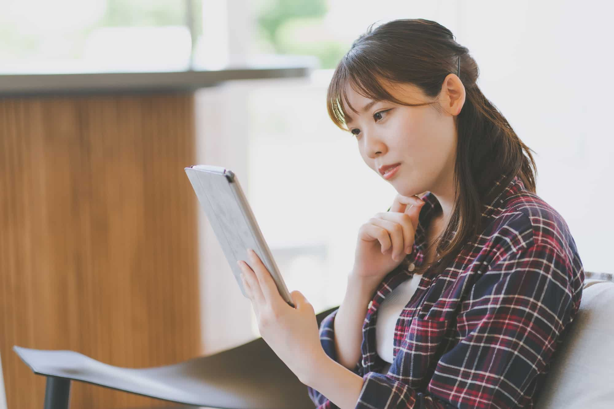 タブレットで調べ物をする20代女性