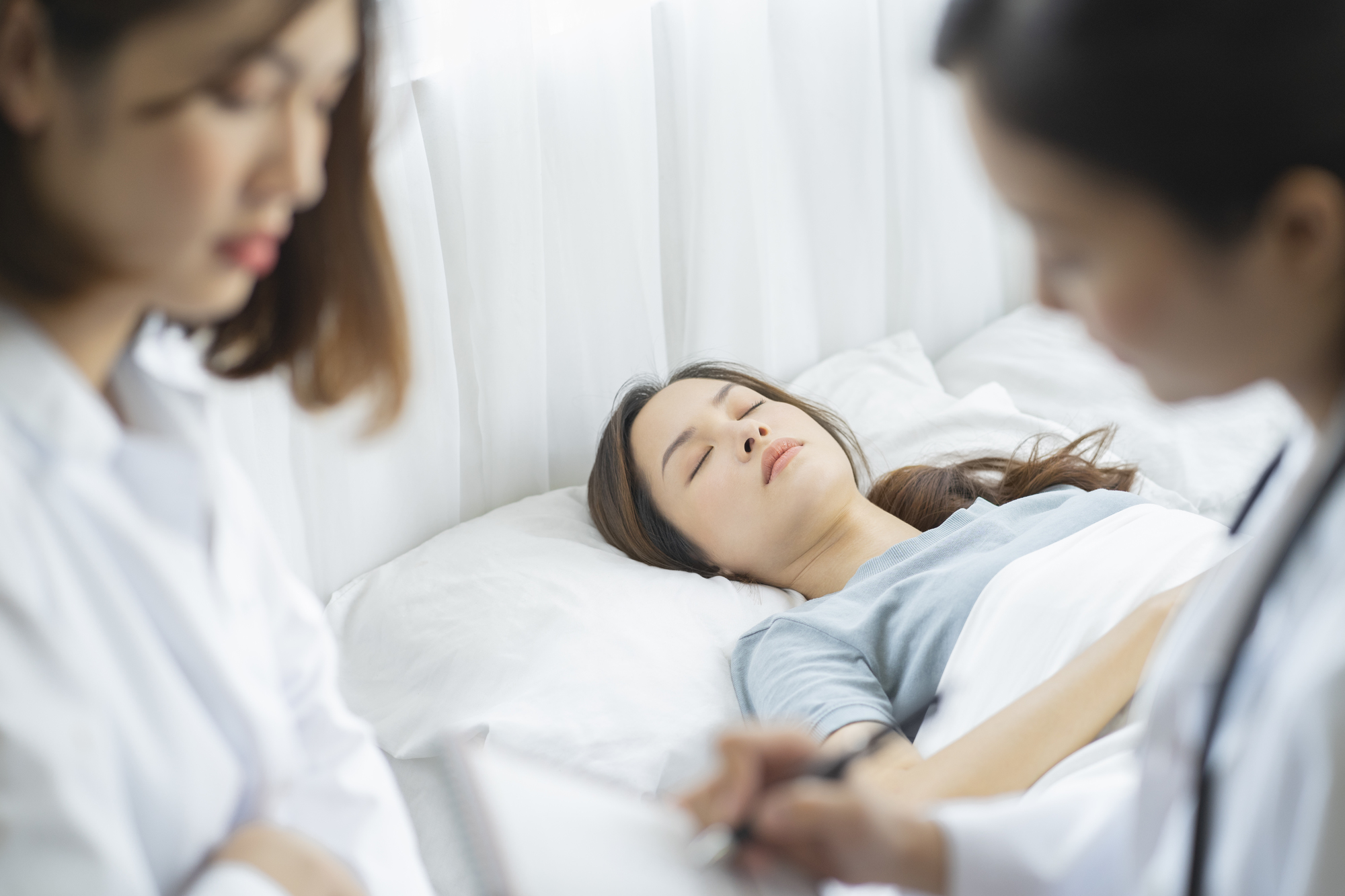 病院のベッドに横になる女性と看護師