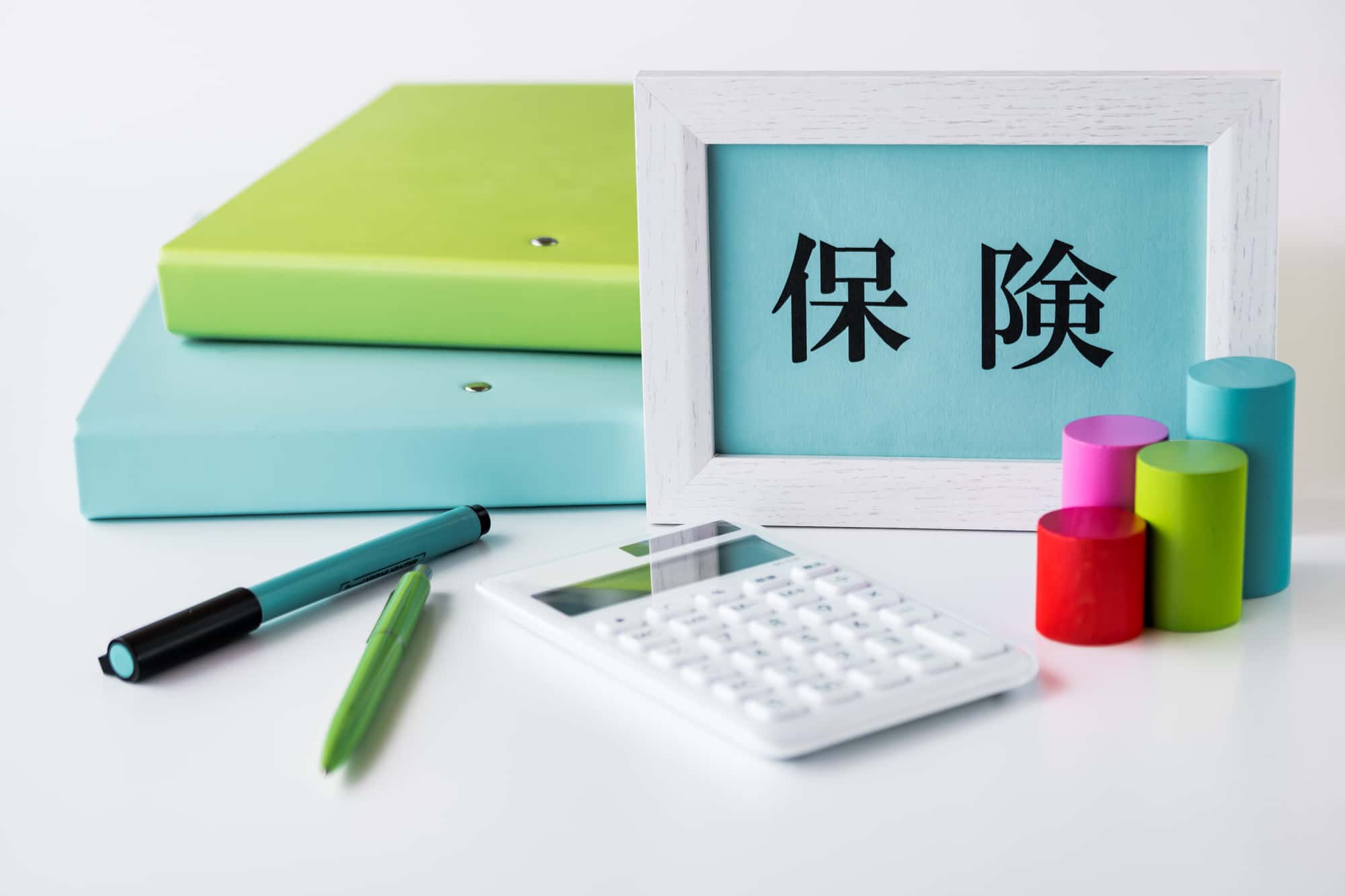 保険と書かれた写真立てとノートとペンのイメージ画像